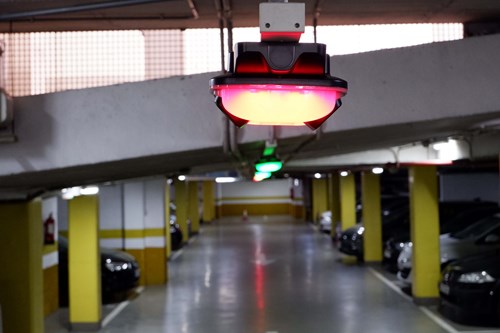 Interior of a parking garage with yellow columns, suspended from the ceiling are red and green lights